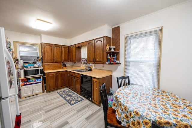 kitchen featuring black dishwasher, stainless steel microwave, freestanding refrigerator, light countertops, and a sink