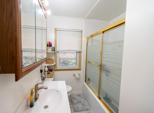 full bathroom with shower / bath combination with glass door, a sink, and toilet