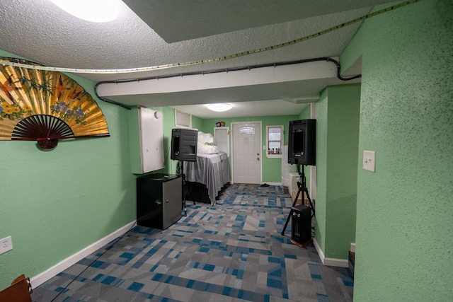 hall with carpet, a textured wall, a textured ceiling, and baseboards