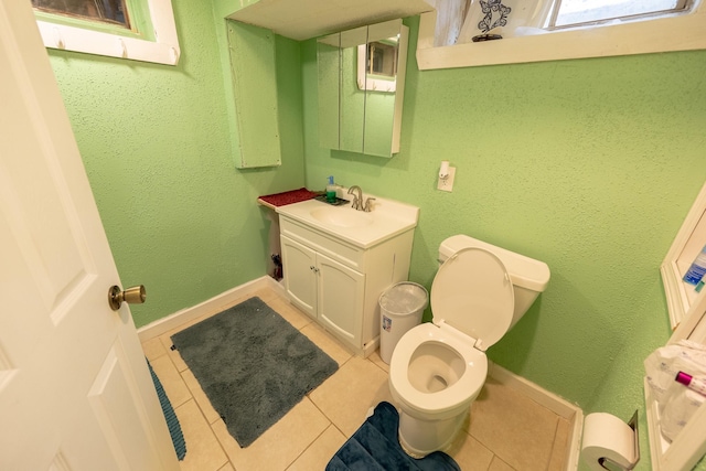 bathroom featuring tile patterned flooring, a textured wall, vanity, and baseboards