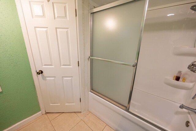 bathroom featuring bath / shower combo with glass door, tile patterned flooring, and baseboards