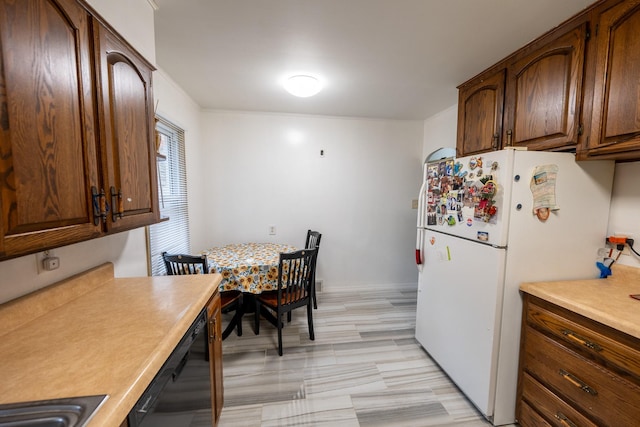 kitchen featuring dishwasher, light countertops, and freestanding refrigerator