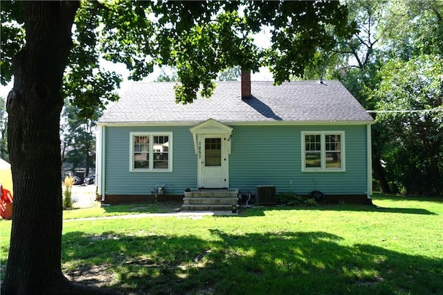 view of front of property featuring roof with shingles, a chimney, a front lawn, and entry steps