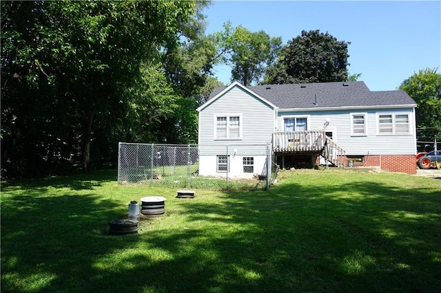 rear view of house with a lawn, fence, and a wooden deck