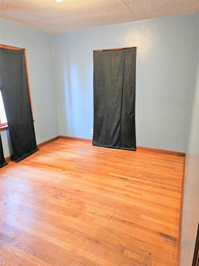 unfurnished room featuring wood finished floors, baseboards, and a textured ceiling