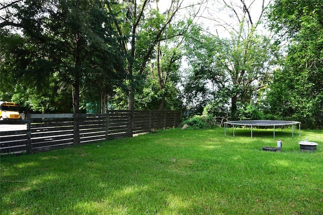 view of yard featuring a trampoline and fence