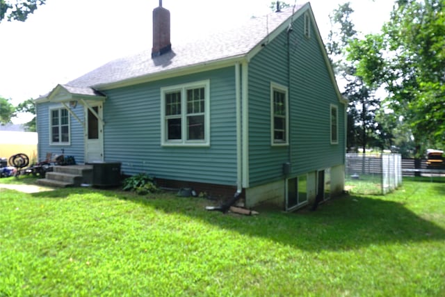 back of house featuring a yard, fence, and a chimney