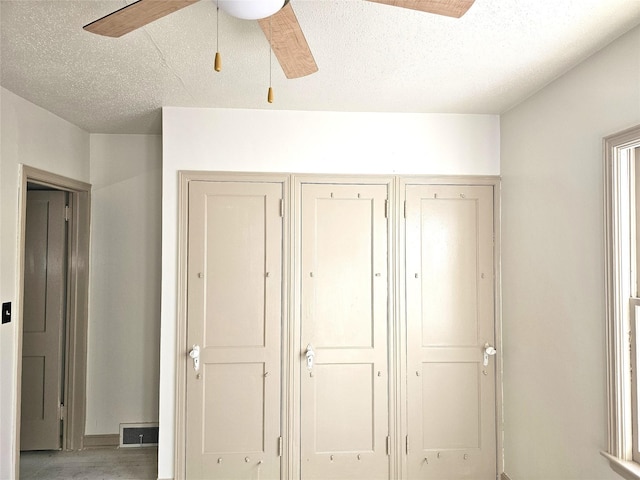 unfurnished bedroom with a ceiling fan, visible vents, and a textured ceiling