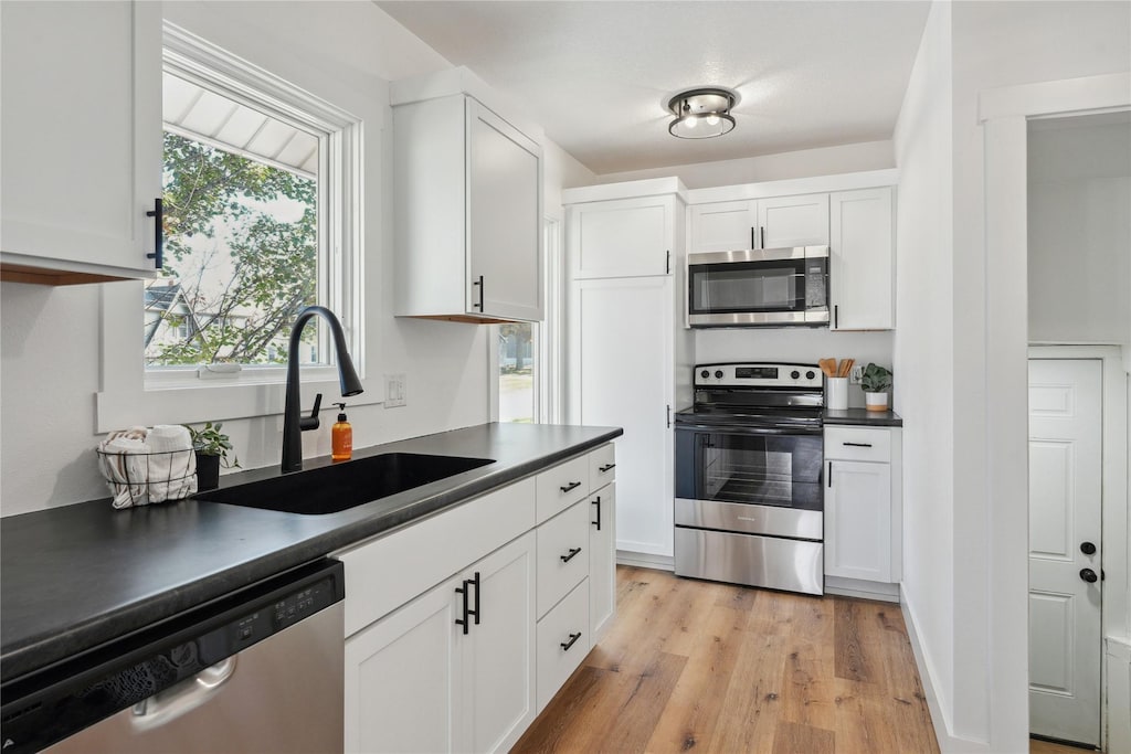 kitchen featuring white cabinetry, stainless steel appliances, sink, and light wood-type flooring