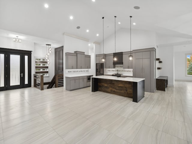 kitchen featuring stainless steel refrigerator with ice dispenser, backsplash, a spacious island, high vaulted ceiling, and hanging light fixtures