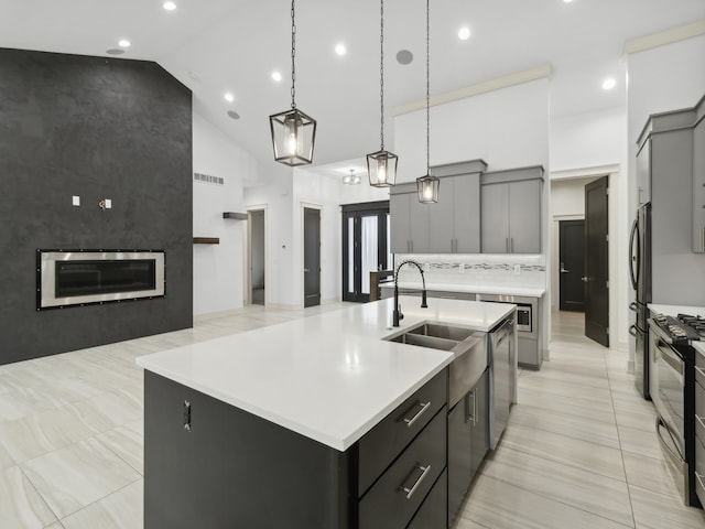 kitchen featuring a large island, sink, high vaulted ceiling, pendant lighting, and appliances with stainless steel finishes