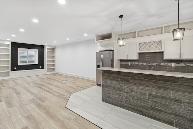 kitchen featuring stainless steel fridge, backsplash, light hardwood / wood-style flooring, and white cabinetry