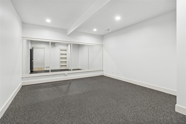 spare room featuring carpet and beam ceiling