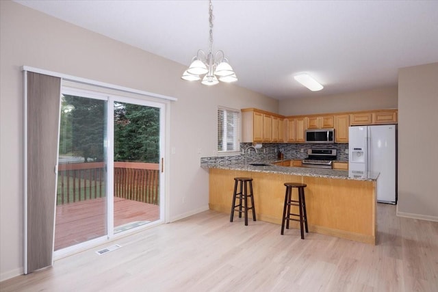 kitchen with kitchen peninsula, appliances with stainless steel finishes, tasteful backsplash, and a notable chandelier