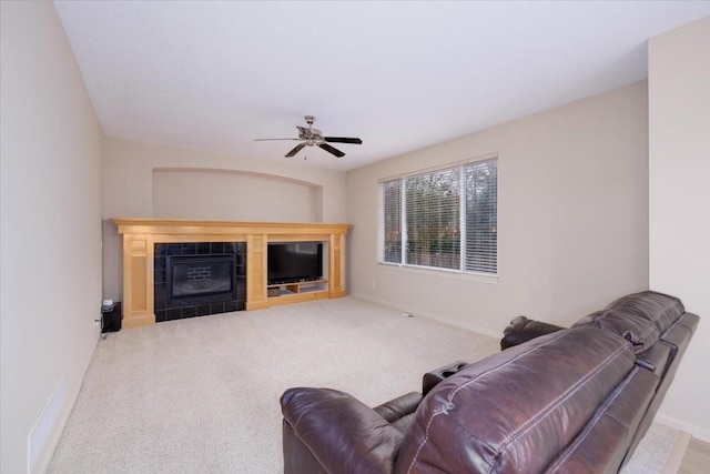 carpeted living room featuring ceiling fan and a fireplace