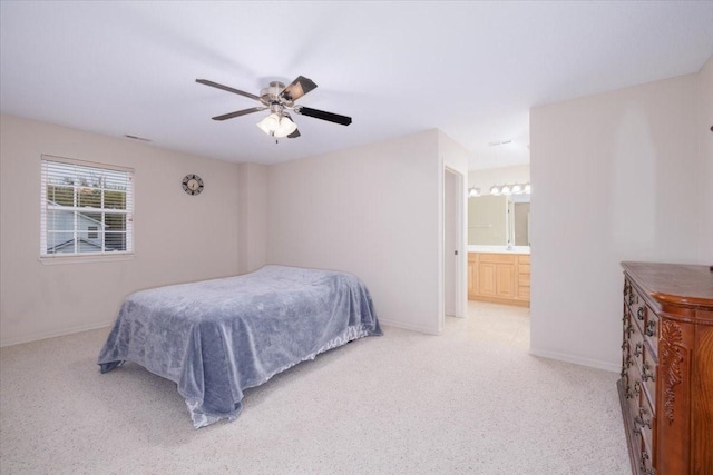 bedroom with ceiling fan, light carpet, and ensuite bath