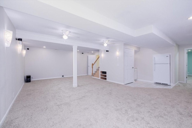 basement with white fridge, ceiling fan, and light colored carpet