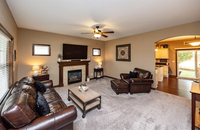 living room with ceiling fan, dark wood-type flooring, and a tiled fireplace