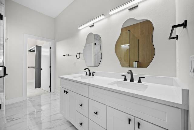 bathroom featuring double vanity, marble finish floor, a walk in closet, and a sink