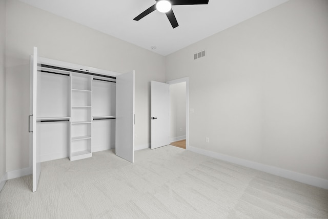 unfurnished bedroom with baseboards, visible vents, light colored carpet, ceiling fan, and a closet