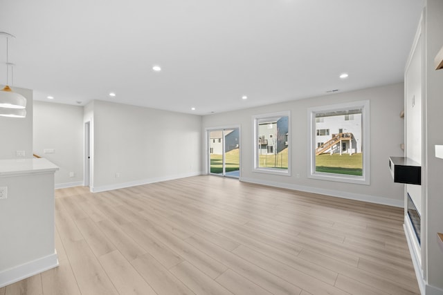 unfurnished living room featuring baseboards, light wood-style floors, and recessed lighting