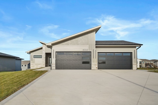 view of front of home featuring a garage, a front yard, concrete driveway, and stone siding