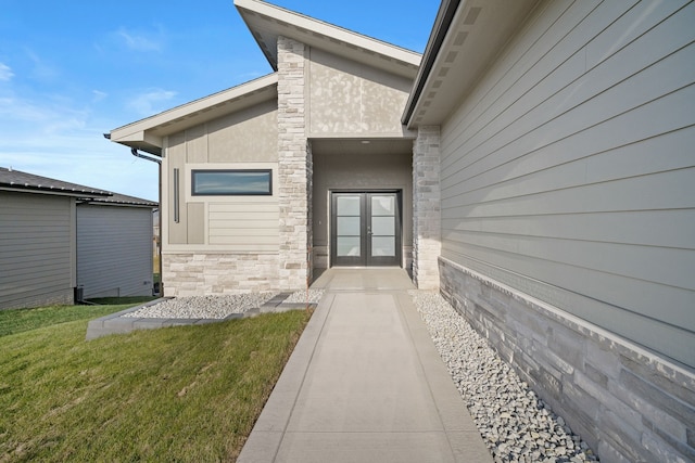 doorway to property featuring stone siding, french doors, a yard, and stucco siding