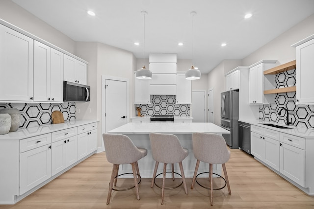 kitchen featuring a sink, white cabinets, appliances with stainless steel finishes, a center island, and open shelves