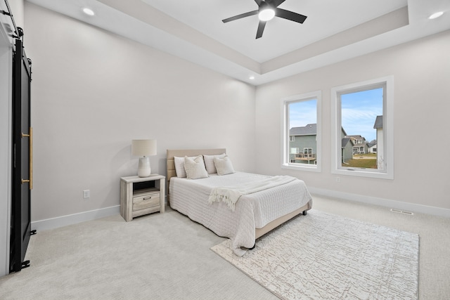 bedroom with baseboards, a tray ceiling, and light colored carpet