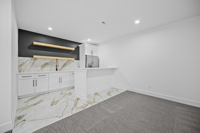 bar with sink, white cabinets, and stainless steel refrigerator with ice dispenser