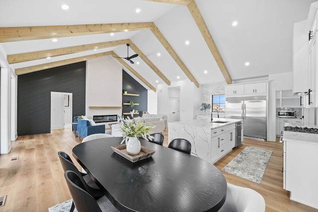 dining room with high vaulted ceiling, sink, ceiling fan, light wood-type flooring, and beam ceiling