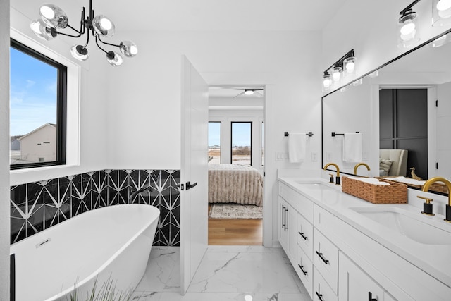 bathroom featuring a chandelier, vanity, tile walls, and a tub