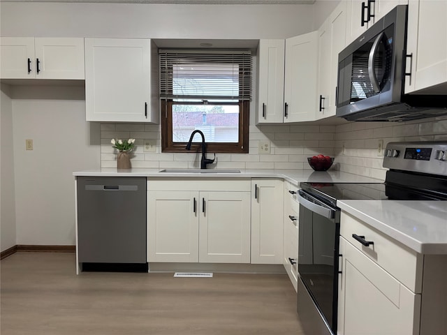 kitchen featuring tasteful backsplash, white cabinetry, appliances with stainless steel finishes, and sink