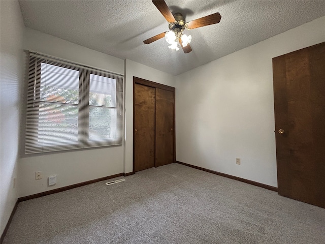 unfurnished bedroom with a textured ceiling, light carpet, ceiling fan, and a closet