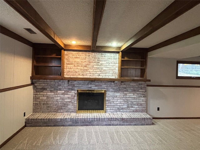 unfurnished living room with a brick fireplace, beamed ceiling, carpet floors, and a textured ceiling