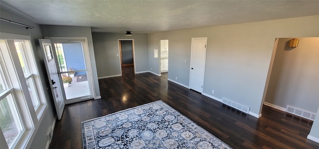 empty room featuring a textured ceiling and dark hardwood / wood-style floors