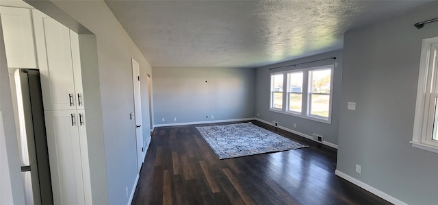 unfurnished room with dark wood-type flooring and a textured ceiling