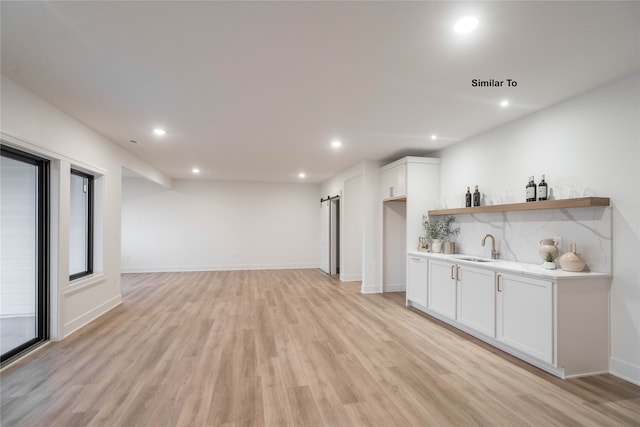 bar featuring white cabinetry, sink, backsplash, and light wood-type flooring