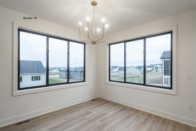 spare room featuring hardwood / wood-style flooring and a notable chandelier