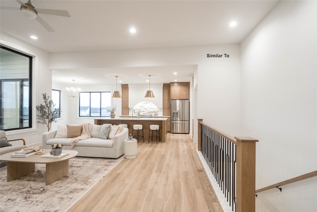 living room featuring sink, ceiling fan with notable chandelier, and light hardwood / wood-style flooring