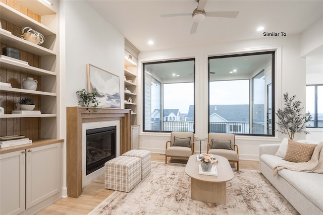 living room with light hardwood / wood-style floors, ceiling fan, a healthy amount of sunlight, and built in features