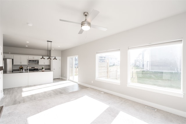 unfurnished living room with ceiling fan and light hardwood / wood-style floors