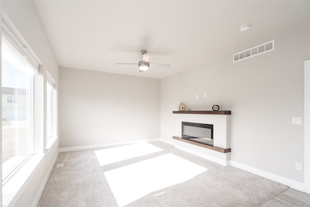 unfurnished living room with light colored carpet and ceiling fan