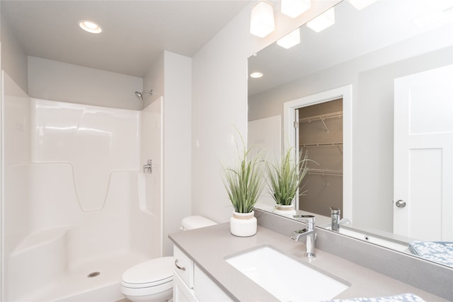 bathroom featuring a shower, vanity, and toilet