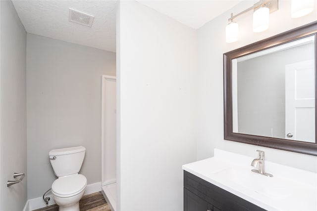 bathroom with hardwood / wood-style flooring, vanity, toilet, and a textured ceiling