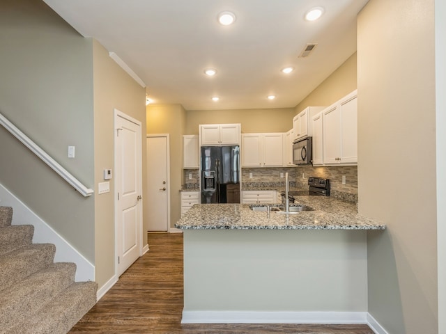 kitchen with black appliances, tasteful backsplash, dark hardwood / wood-style flooring, white cabinets, and kitchen peninsula