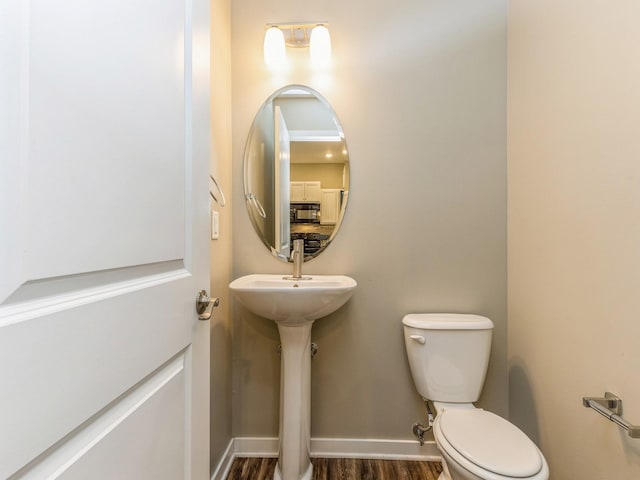 313 SW 7th St Unit 107, Des Moines, IA 50309 - bathroom featuring toilet, wood finished floors, and baseboards