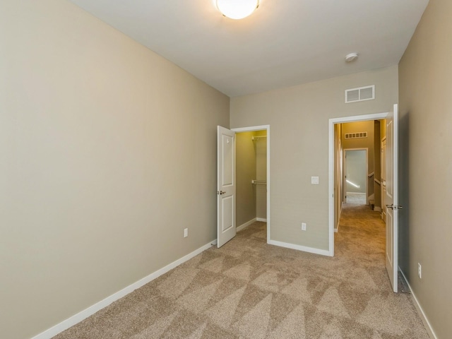 313 SW 7th St Unit 107, Des Moines, IA 50309 - unfurnished bedroom with light colored carpet, baseboards, and a walk in closet