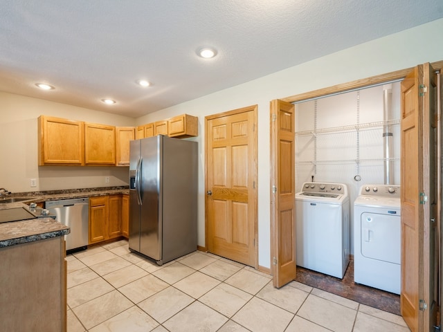 kitchen with separate washer and dryer, stainless steel appliances, a textured ceiling, light tile patterned floors, and sink