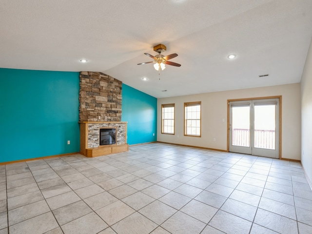 unfurnished living room with a stone fireplace, vaulted ceiling, light tile patterned floors, and ceiling fan